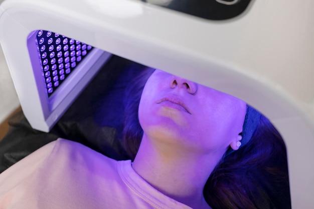 Woman receiving LED light therapy on face for skincare treatment.