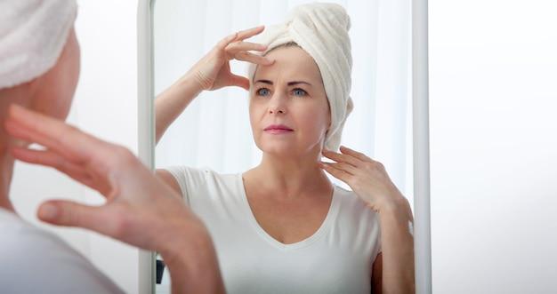 Woman examining her face in mirror after shower