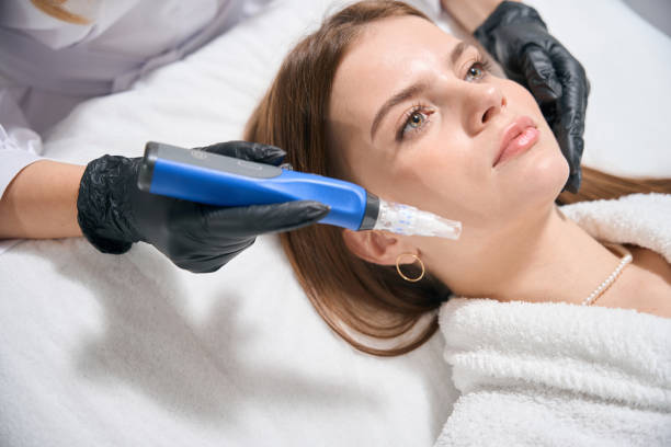 A woman receiving a facial treatment with a specialized device in a spa setting.